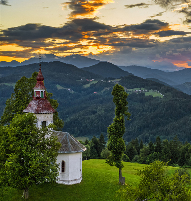 A small church on a bright green grassy hilltop.